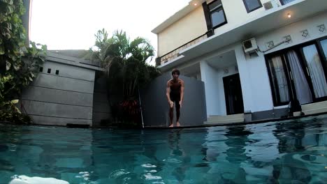 slow motion shot of a man running and jumping and doing a belly flop into a swimming pool