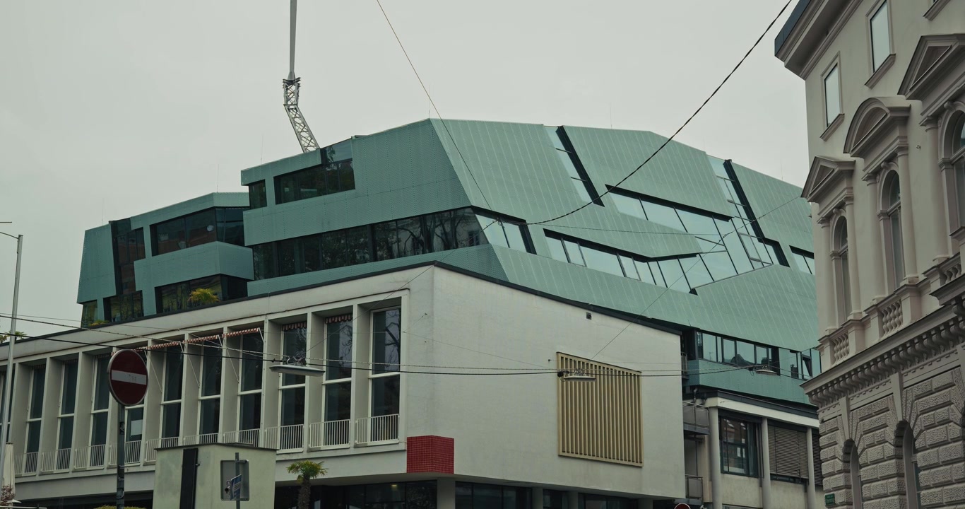 Moderna arquitectura angular del edificio Mausefalle en Graz, Austria, con diseños geométricos únicos y paneles de vidrio contra un cielo nublado.