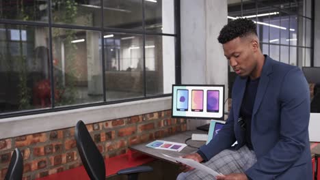 Happy-african-american-male-creative-reading-document-at-casual-office,-in-slow-motion