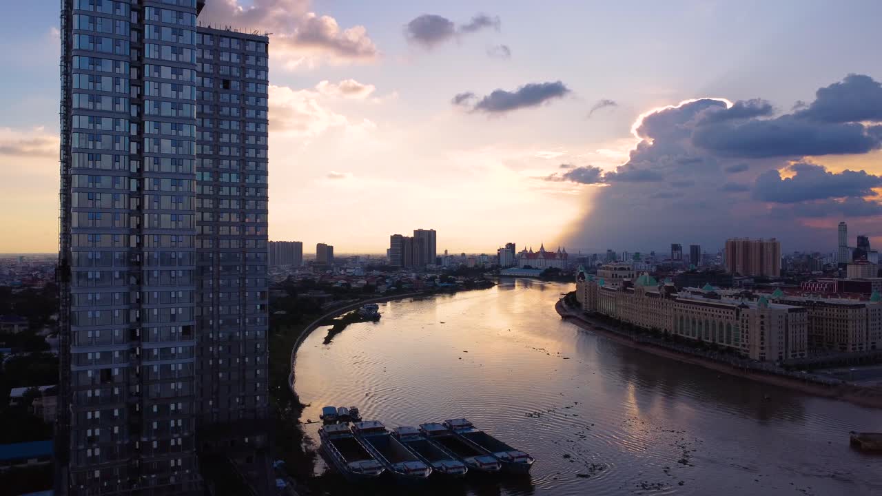High-rise building by the Tonle Bassac River at sunset with Phnom Penh cityscape in the background