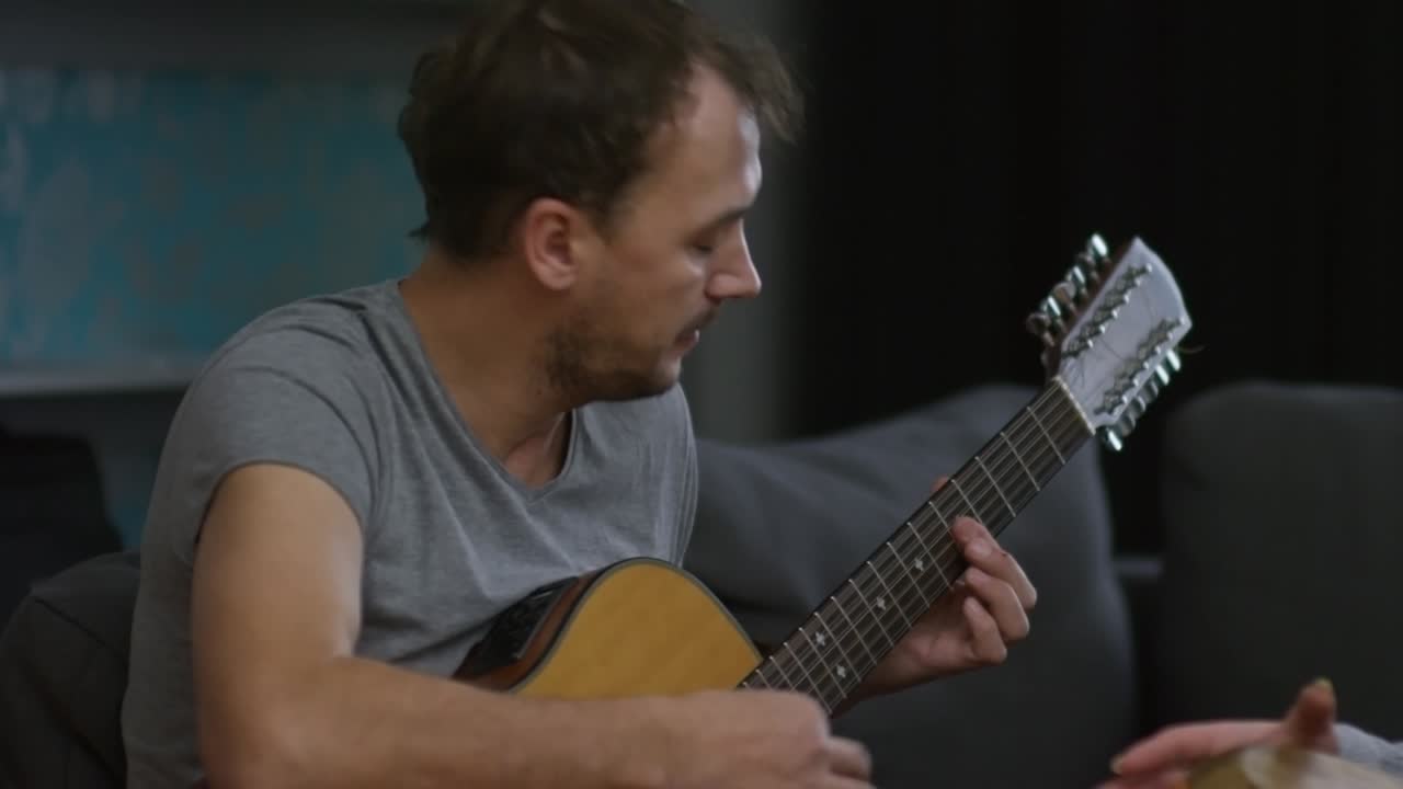 집에서 기타와 민족 드럼을 연주하는 부부