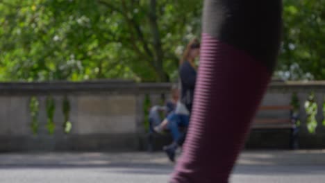 Defocused-Shot-of-People-and-Traffic-Moving-In-Front-of-Woman-Sat-On-Bench-01