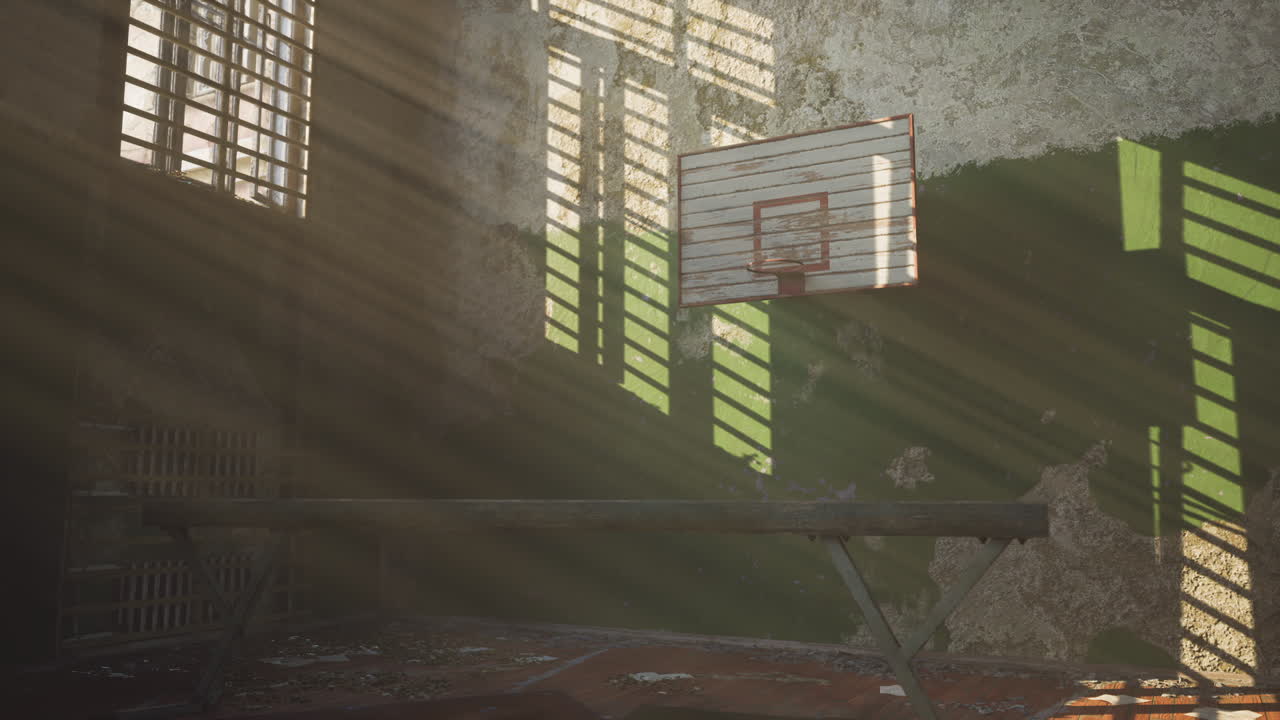 Abandoned basketball court with sunlight streaming through dusty windows