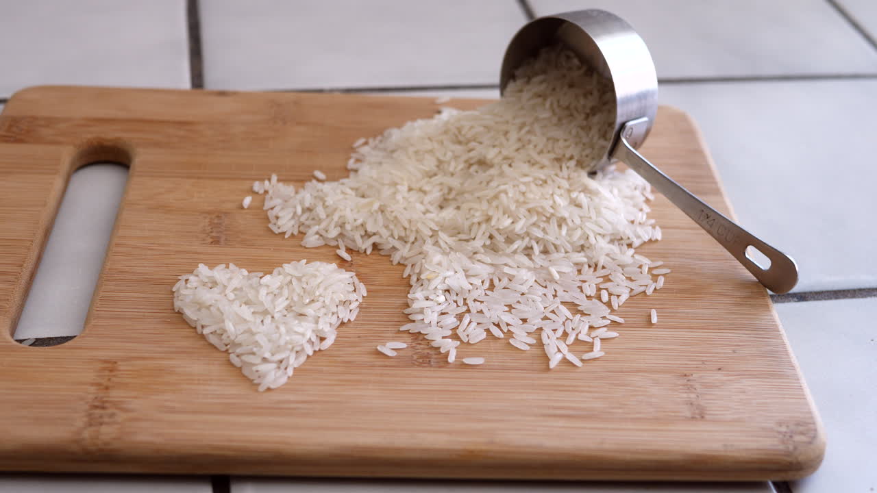 grano de arroz blanco en un corazón con una mano vertiendo ingredientes de un vaso medidor deslizado hacia la izquierda