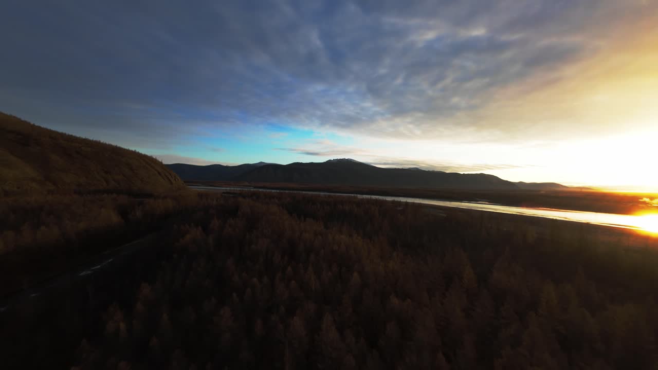 Soaring high above the serene landscapes of Yakutia, witness the stunning transformation of the wilderness as the sun sets. Nature's beauty unfolds amidst majestic mountains and tranquil rivers.