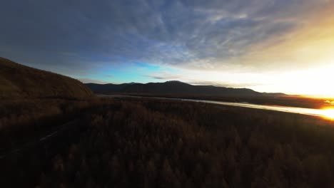 soaring high above the serene landscapes of yakutia, witness the stunning transformation of the wilderness as the sun sets. nature's beauty unfolds amidst majestic mountains and tranquil rivers.