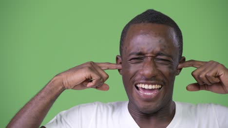 young african man covering ears from loud noise