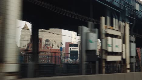 looking out the window of a subway car as it passes over the manhattan bridge with new york city iconic skyline buildings in view