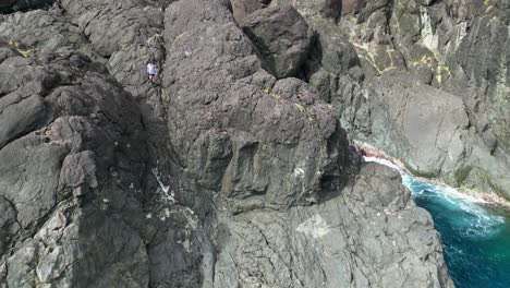 Abenteuerlustiger-Reisender-Geht-Die-Klippe-Hinunter,-Um-Den-Blick-Auf-Das-Meer-Der-Tropischen-Insel-Zu-Genießen