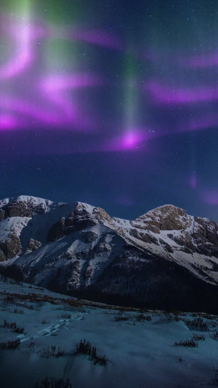Vivace aurora boreale sopra montagne innevate di notte