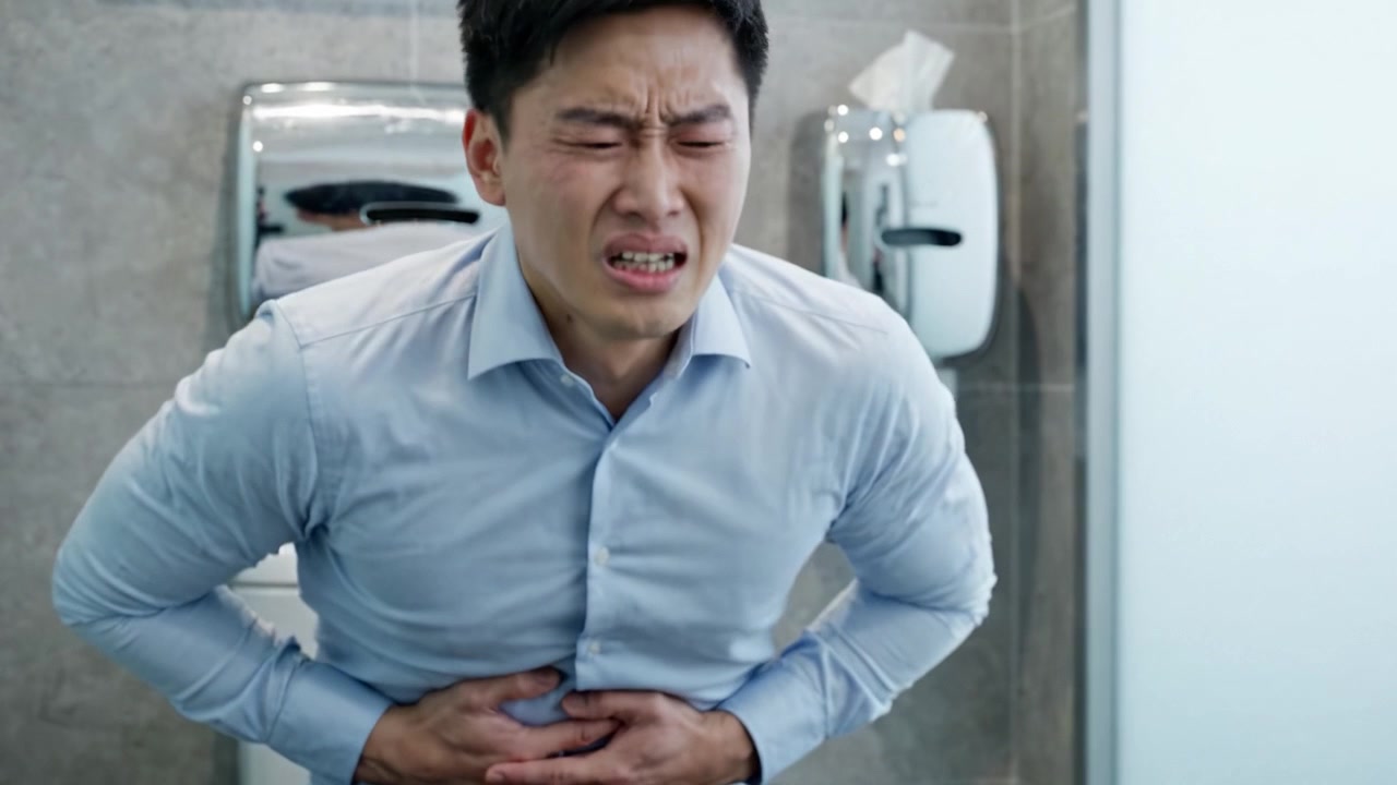 苦悩する男性：プロフェッショナルな服装と穏やかな環境にもかかわらず、トイレで激しい腹痛を経験する