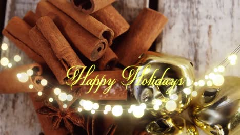 Animation-of-text,-happy-holidays,-in-yellow,-over-string-lights-and-cinnamon-sticks