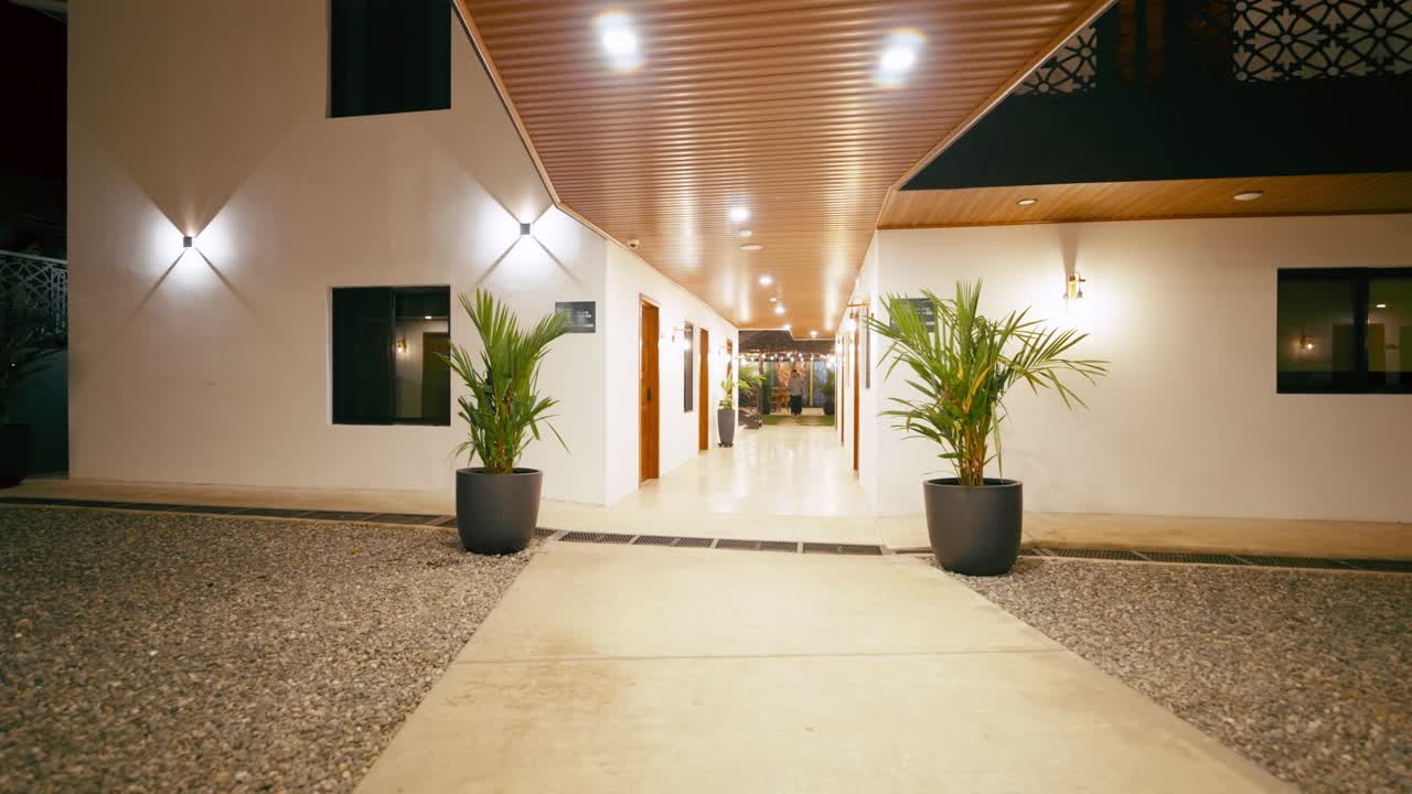 Esterno moderno di un hotel con vialetto e luci calde di notte