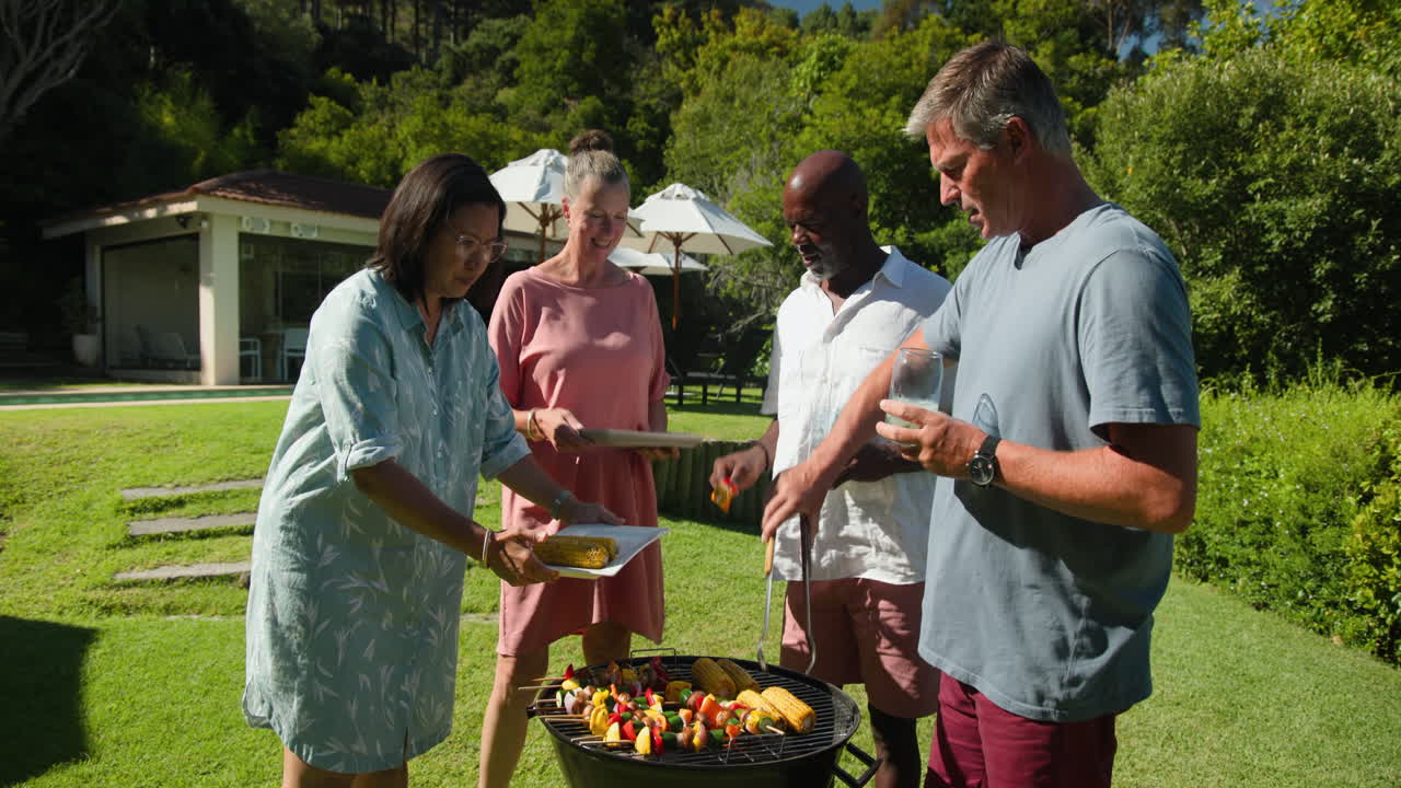 Diverse group of diverse seniors enjoying in garden barbecue, grilling vegetables and corn