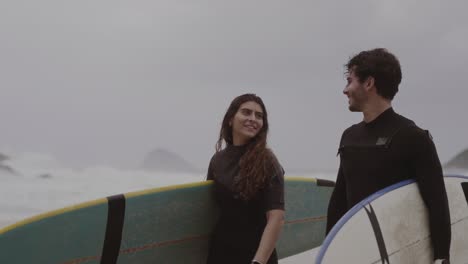 couple walking on the beach with surfboards
