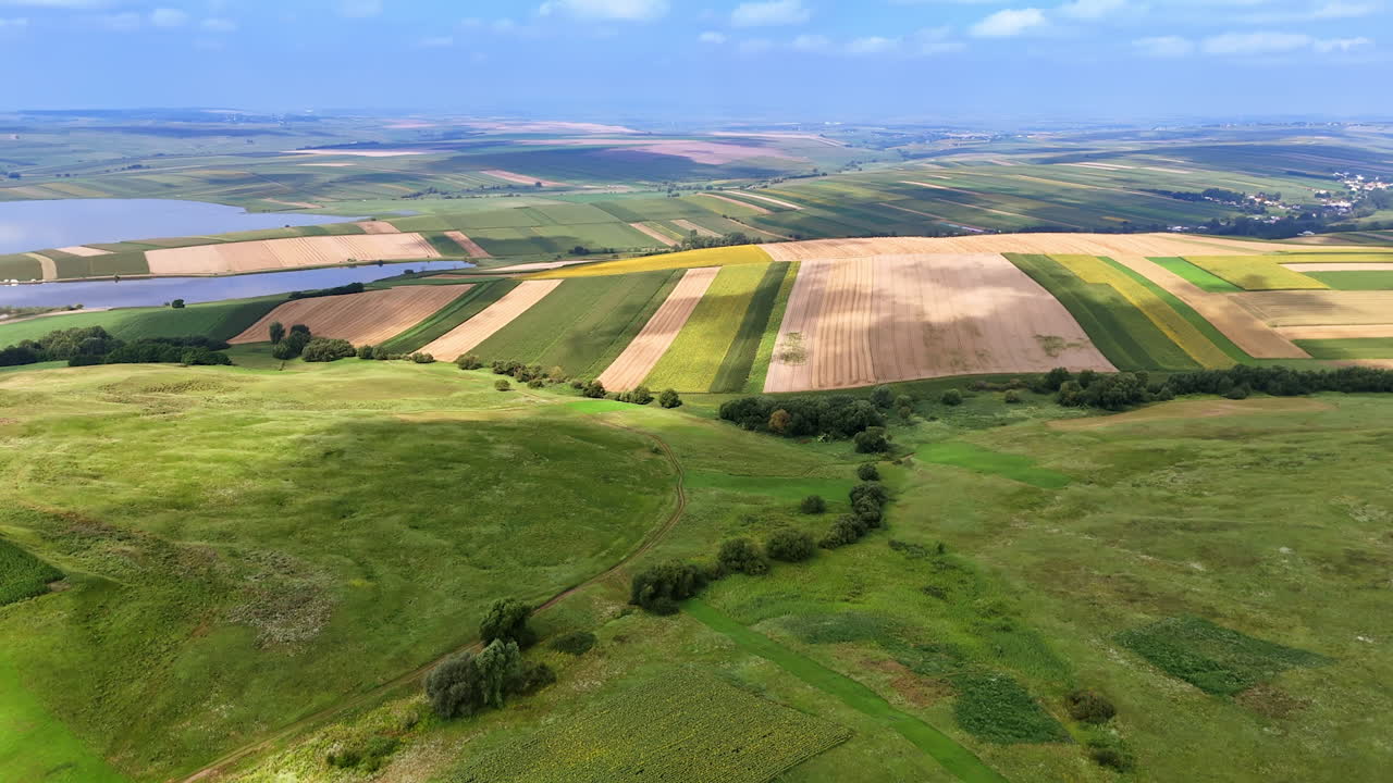 Expansive countryside landscape with diverse farmland views. Aerial view showcases vibrant fields and rolling hills in a rural area during clear weather, highlighting agriculture