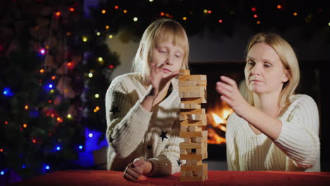 mom and daughter play a board game with wooden blocks