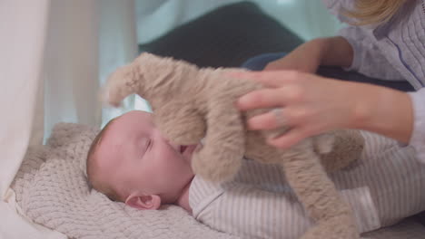 loving mother playing game with  baby son and soft toy lying on rug in homemade camp in child's bedroom at home - shot in slow motion