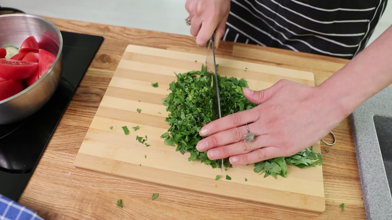 Person chopping fresh herbs on a wooden cutting board
