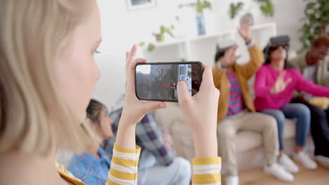 Diverse-group-of-teenage-friends-recording-with-smartphone-using-vr-headsets-at-home,-slow-motion