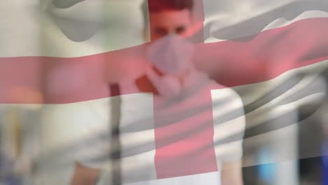 Animation-Der-Flagge-Englands,-Die-Während-Der-Covid-19-Pandemie-über-Einem-Mann-Mit-Gesichtsmaske-Winkt