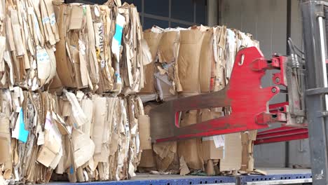 fork lift with bale clamp picks up paper and cardboard at recycling center