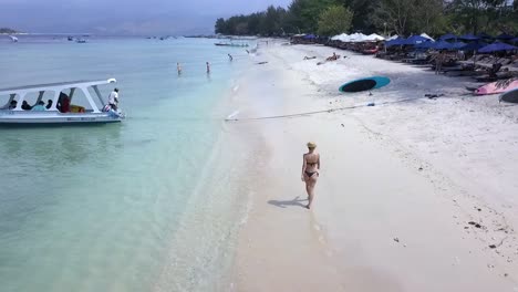 slow motion woman walking with hat on a paradise sandy beach fantastic aerial view flight pursuit flight drone footage at gili t beach indonesia at summer 2017 cinematic from above by philipp marnitz