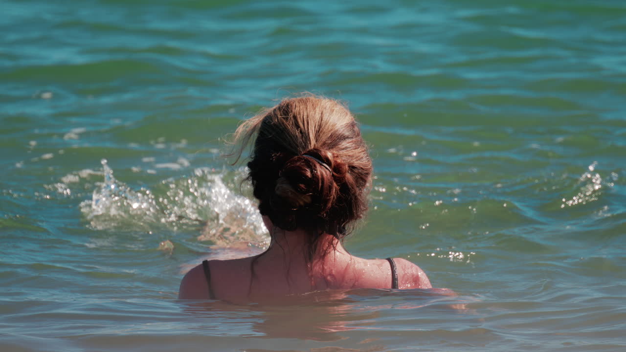 Woman swimming in the calm blue sea under sunlight in Cannes, France