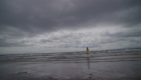 Una-Niña-Corre-Hacia-El-Agua-Del-Mar,-Luego-Gira-Y-Vuelve-Corriendo,-A-Cámara-Lenta