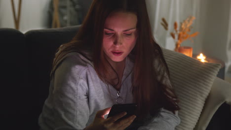 Anxious-Woman-Sitting-On-Sofa-At-Home-At-Night-Looking-At-Mobile-Phone-Concerned-About-Social-Media-Or-Bad-News-6