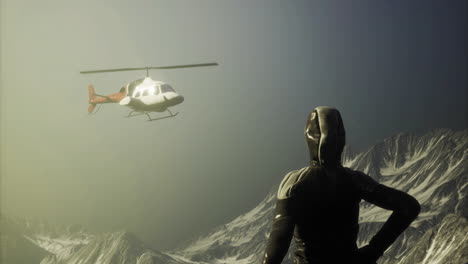 helicóptero flotando sobre picos de montañas nevadas cerca de un escalador al atardecer