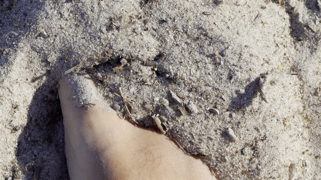 Close up of a man's foot playing in the sand at the beach