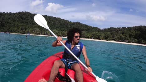 Frontside view of a strong male tourist paddling on the ocean in his Kayak. Vacation travel 4k. Perhentian Islands, Malayisa.