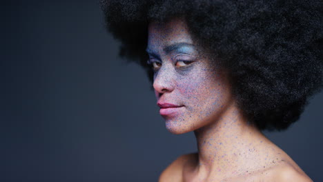 retrato de una hermosa mujer afroamericana con rostro exótico, pintura corporal, arte corporal, mujer misteriosa con maquillaje colorido, luz parpadeando en un fondo oscuro, concepto de expresión creativa