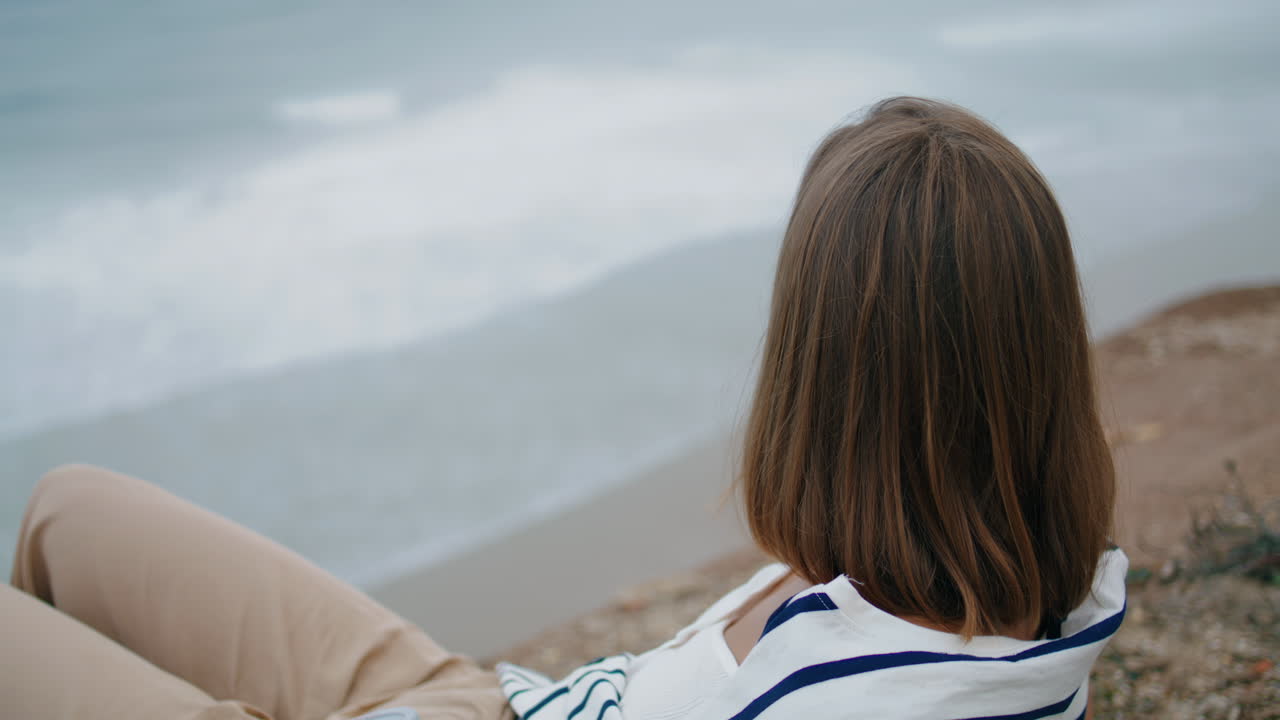 바다 절벽을 즐기는 소녀 수직 클로즈업. 웃는 관광객이 바다에서 포즈를 취하고 있습니다.