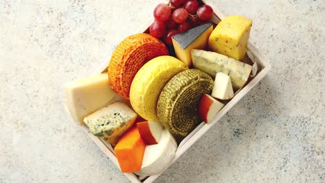 fresh and delicious different kinds of cheeses placed in wooden crate with grapes