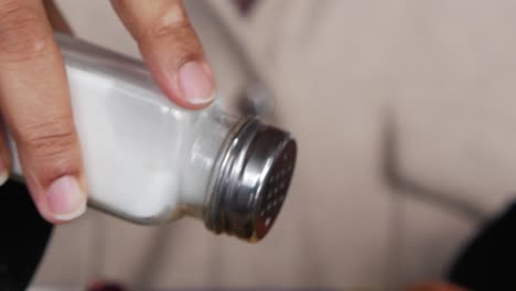 person seasoning food with salt