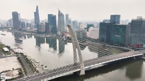 drone view of the modern cable-stayed thủ thiêm 2 bridge spanning the saigon river in ho chi minh city, vietnam, with iconic skyline landmarks like bitexco tower and landmark 81 in the background