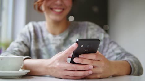 hermosa joven usando su teléfono móvil en una cafetería. y sonriendo. mujer usando una aplicación en un teléfono inteligente en una cafetería bebiendo café y