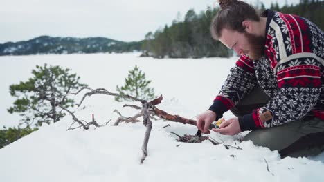 person making a fire using dry tree branches in snow winter landscape