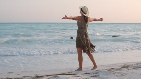 woman staying with wide open arms at beach. happy girl walking at seaside.