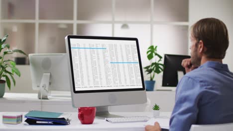 Caucasian man sitting at desk coding data on laptop