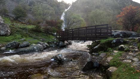 waterfall rocky river flowing water slow motion cascades under wooden bridge in national park