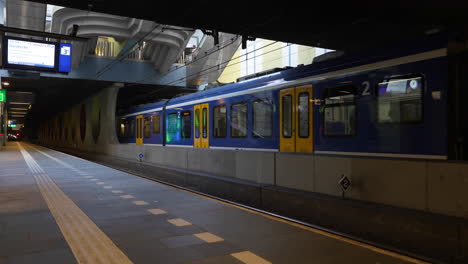 empty platform of rotterdam blaak with train leaving the station