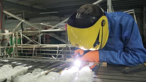 man wearing mask welding in a workshop. metal workers use manual labor. skilled welder. welder is welding the stainless steel pipes in the factory. welder industrial part in factory.