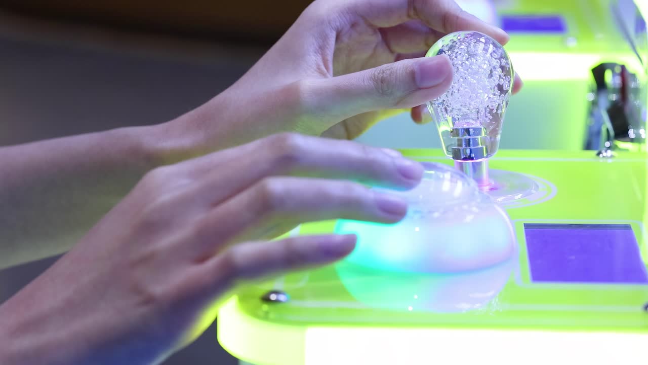 Close-up of hands interacting with illuminated arcade controls, featuring vibrant colors and dynamic lighting effects.