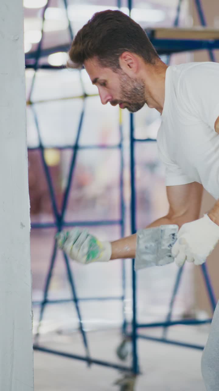 A Skilled Painter Applying Finishing Touches to a Wall, Showcasing Precision and Effort in a Brightly Lit Interior Space of Renovation