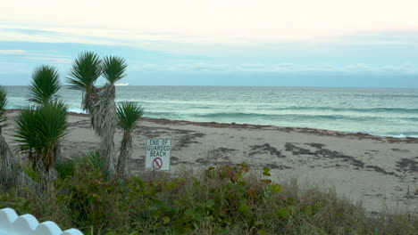 tropical beach at sunset with an end of guarded beach sign posted