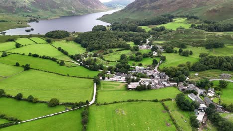 a drone view of buttermere village, cumbria. captures the scenic, rural buildings,lake and roads in the heart of the lake district