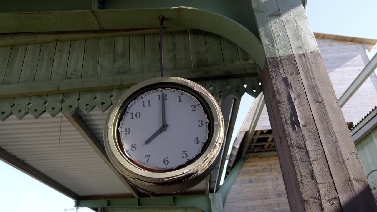 Old vintage train station waiting room with a large clock hanging from a wooden pole in the center of the room